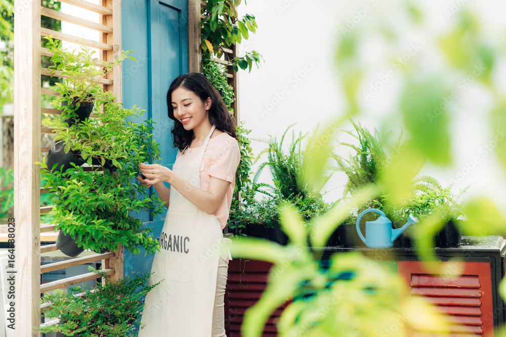 花园里穿着围裙的绿色灌木修剪器的年轻职业女性