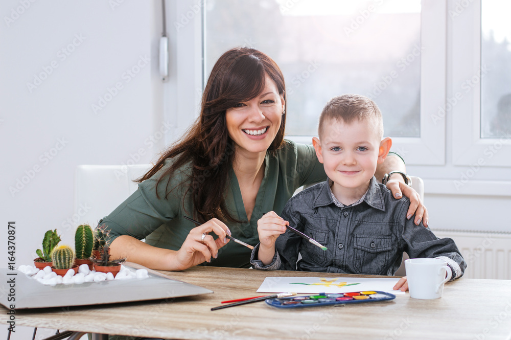 Mom and son painting on paper together at home