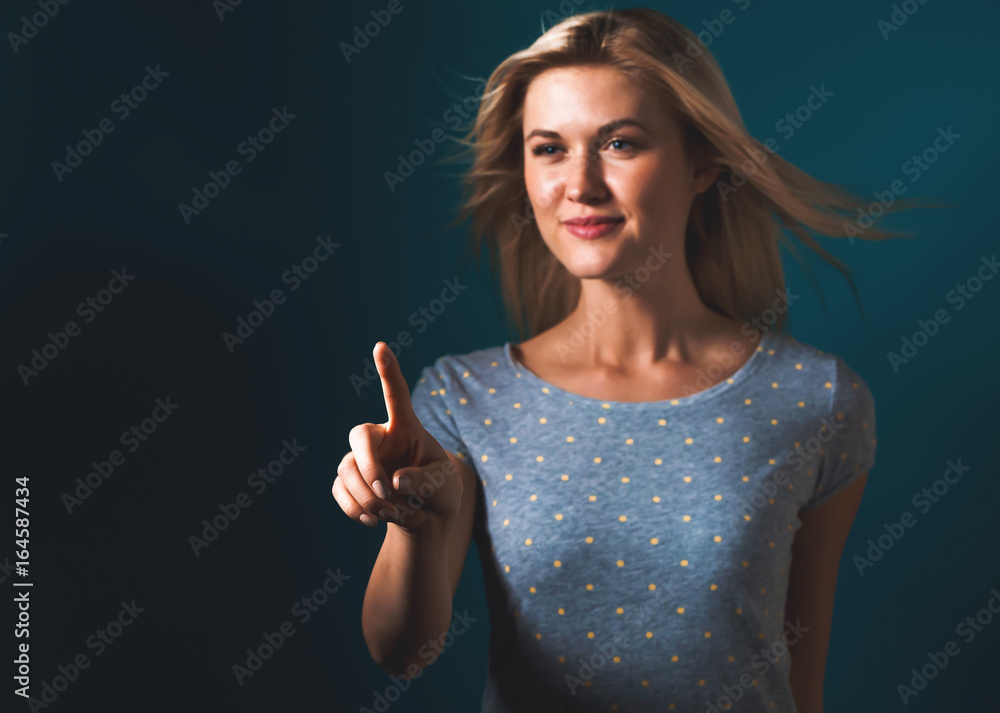 Young woman pointing something on a blue background