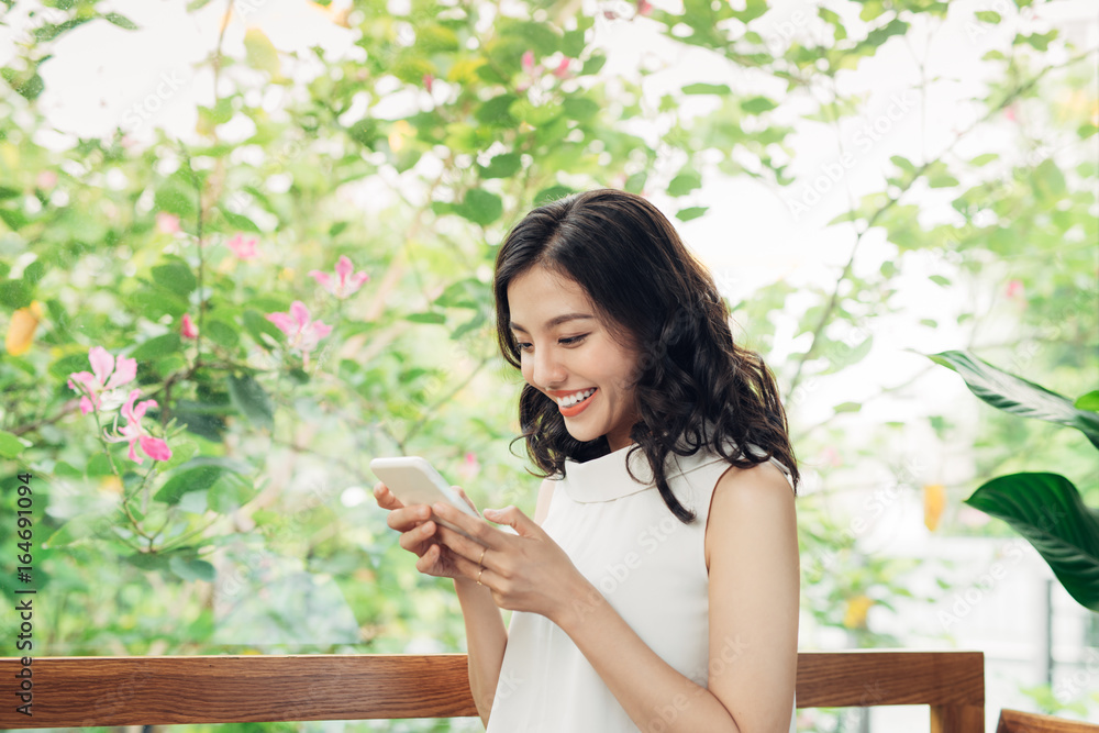 自信的年轻亚洲女性，穿着时髦的休闲服，在电话里打字。