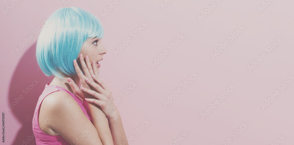 Portrait of a woman in a bright blue wig on a pink background