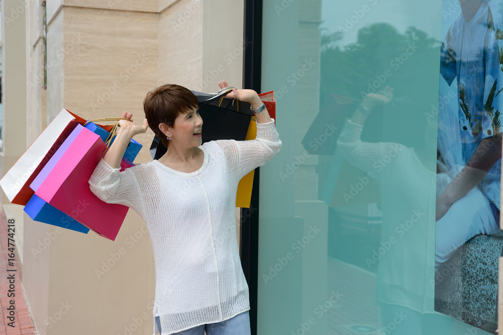 Happy woman at the mall holding shopping bags and smiling