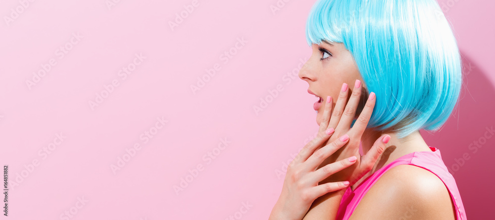 Portrait of a woman in a bright blue wig on a pink background