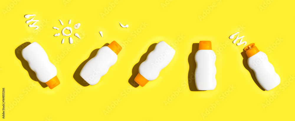 Sunscreen bottles arranged on a bright yellow background