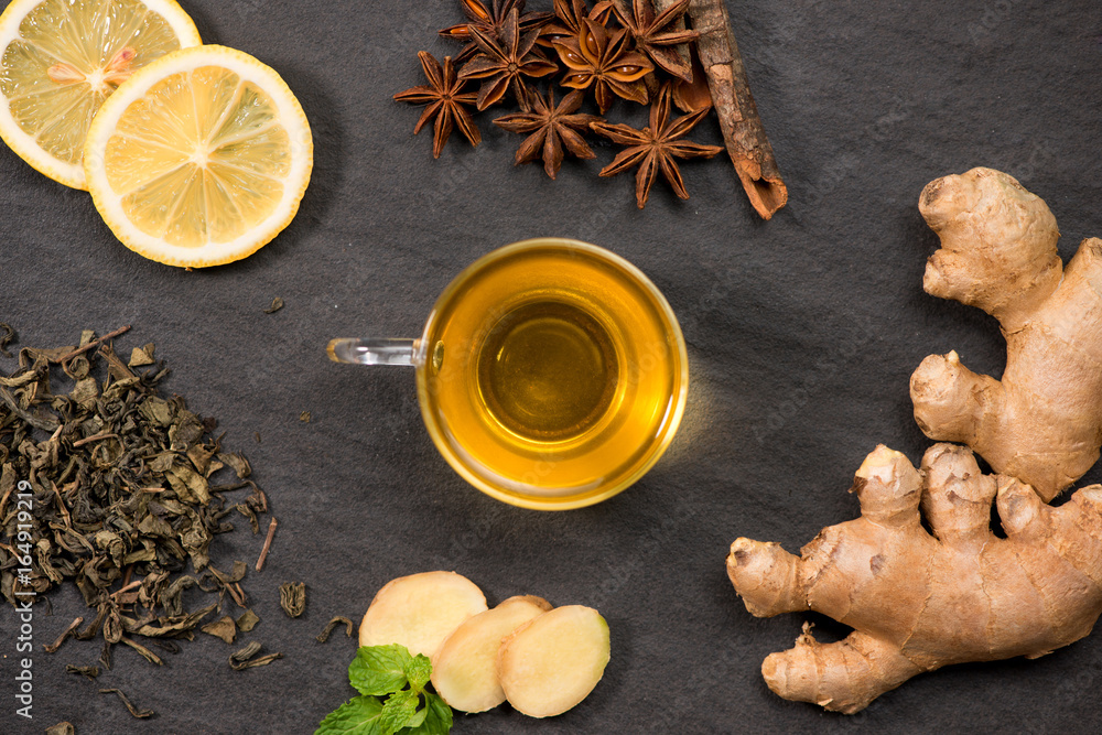 Cup of ginger tea with lemon and honey on dark stone background