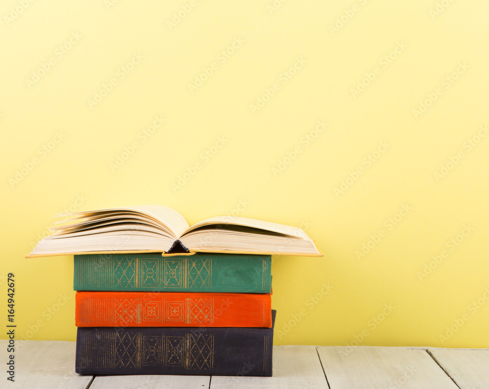 education and wisdom concept - open book on wooden table, color background