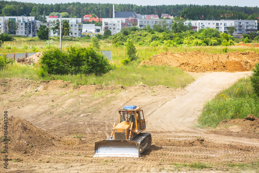 Yellow bulldozer with caterpillar moving ground with scoop