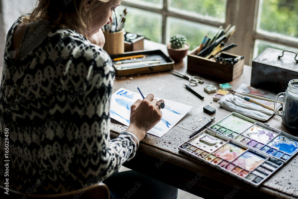 Rear view of woman drawing with water color on paper