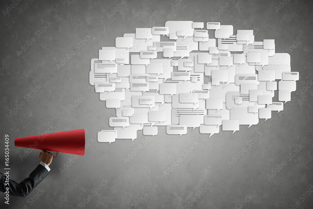 Hand of businesswoman holding red paper trumpet and speech cloud coming out