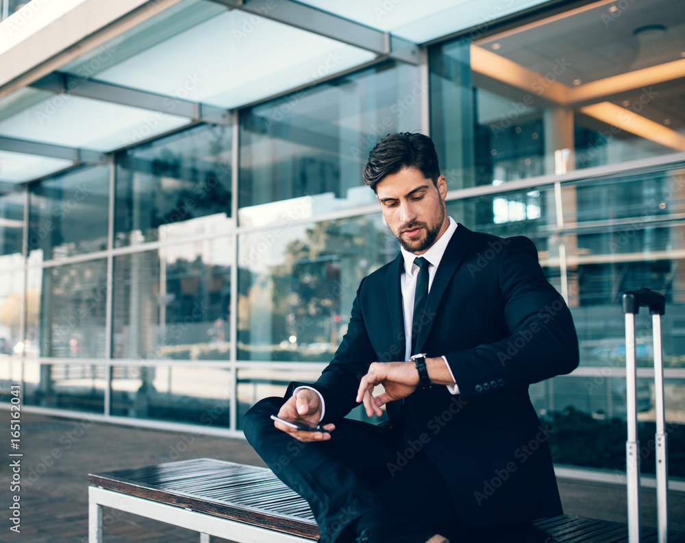 Young businessman checking time at airport