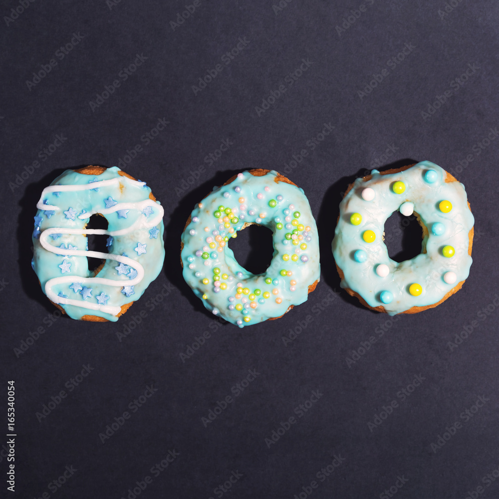 Colorful glazed donuts on a chalky black background