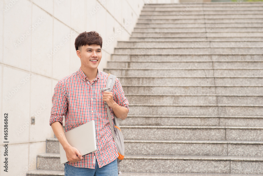 大学校园里男学生拿着笔记本电脑