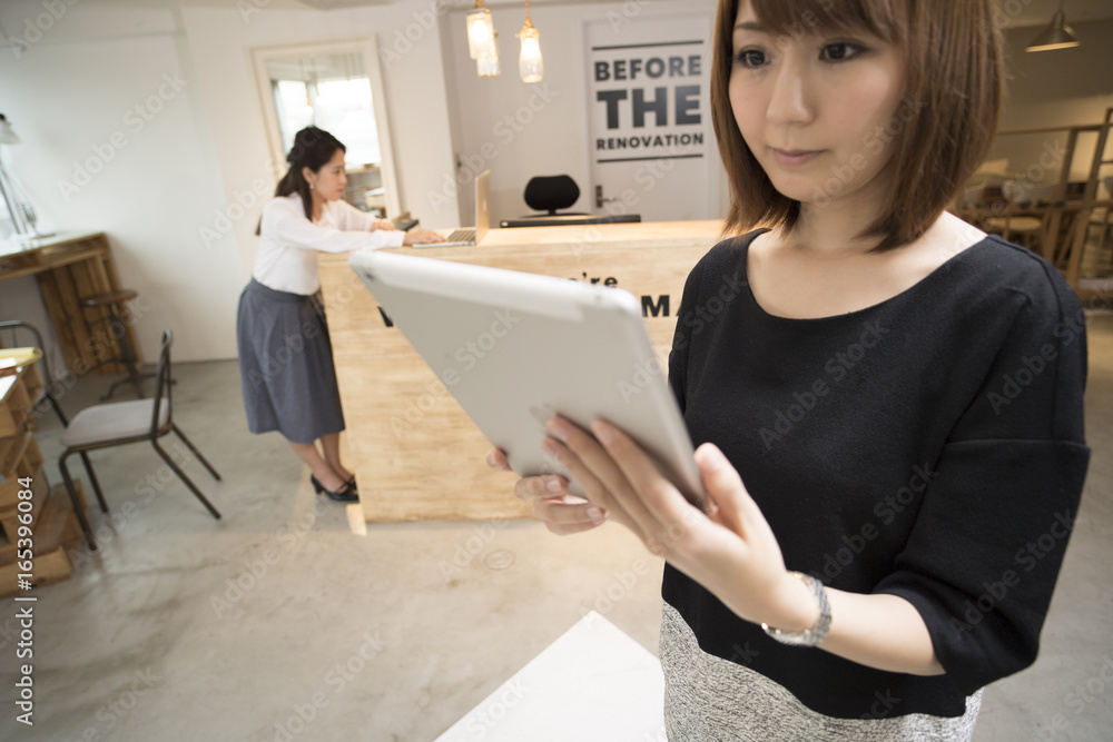 A young woman stands holding a tablet