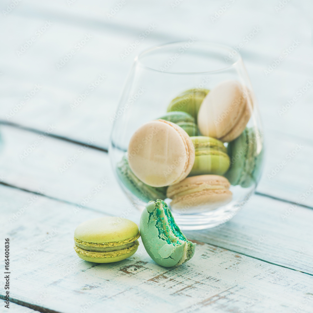 Colorful pastel pink, green and blue French macaron biscuits in glass over light blue painted rustic