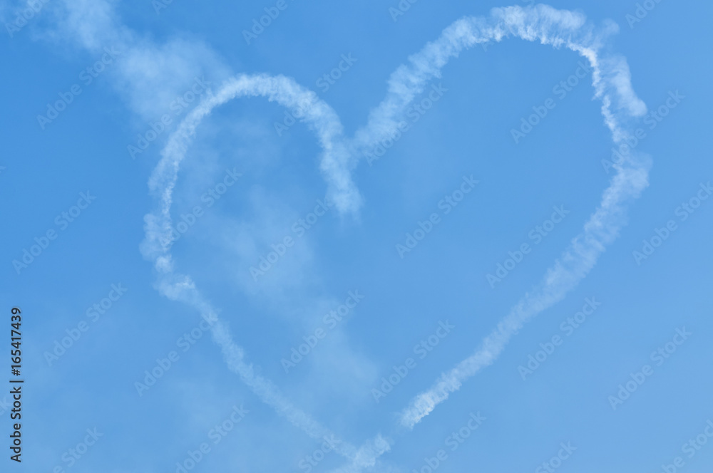 View on sport plane vapour trail in shape of loving heart. Made by two sport planes white vapour tra