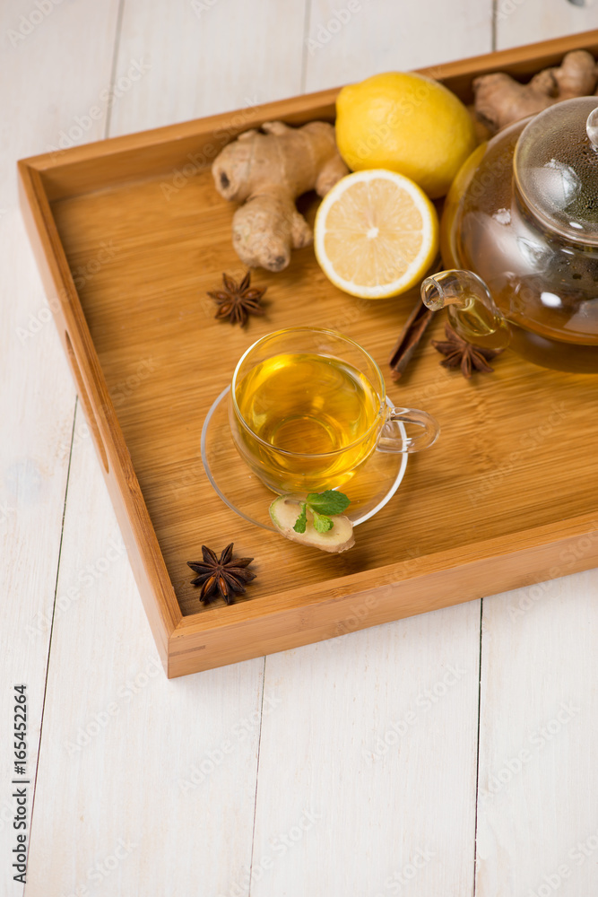 Cup of ginger tea with lemon and honey on white wooden background.