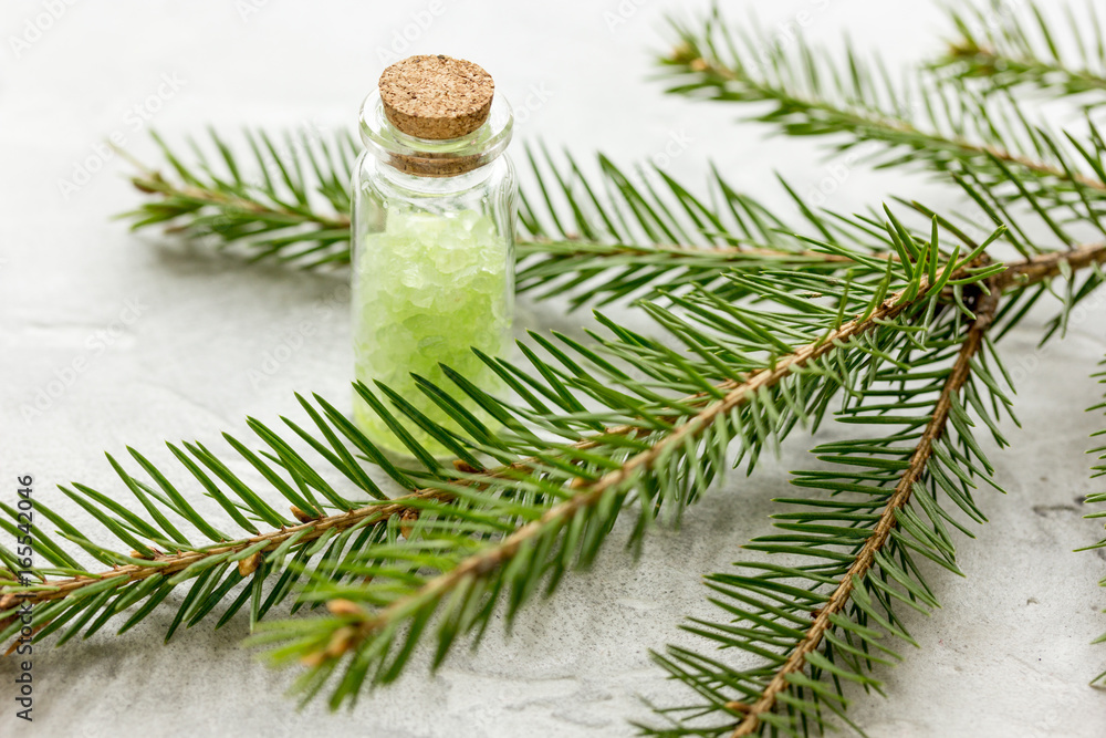 cosmetic spruce salt in bottles with fur branches on white table background