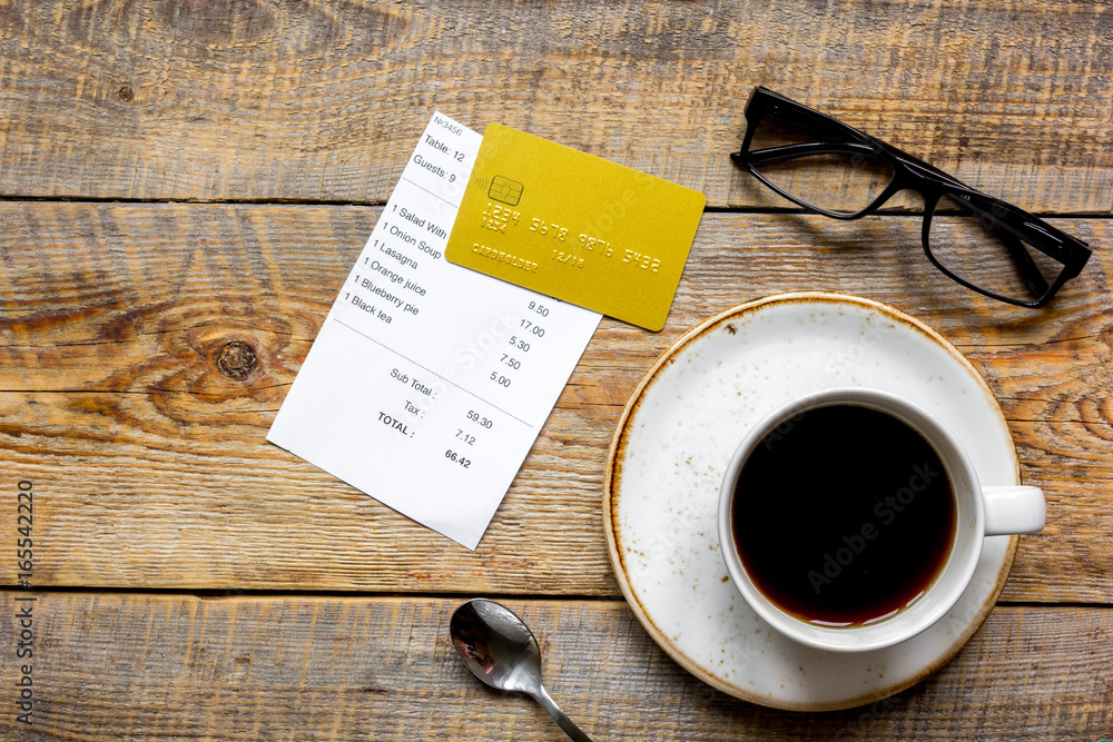 credit card for paying, coffee and check on cafe wooden desk background top view