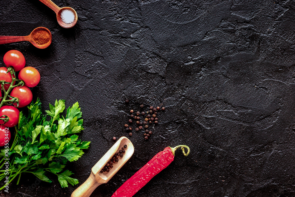 spices in wooden spoon on dark background top view