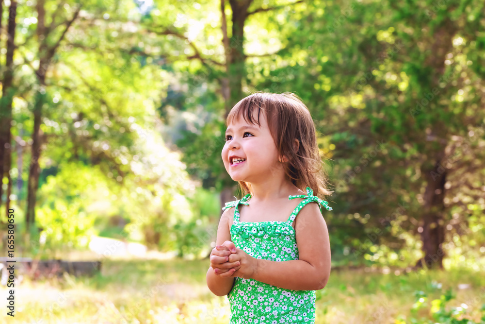 Happy toddler girl wearing bathing suit playing outside