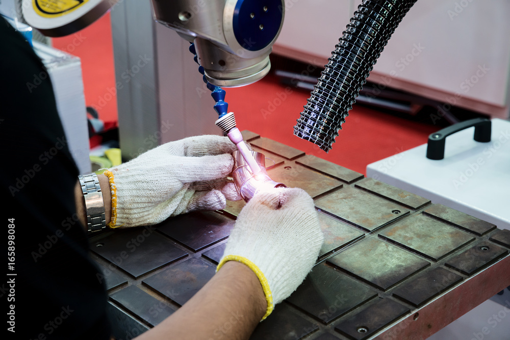 Worker using repair mold and die part by Laser welding machine in factory.