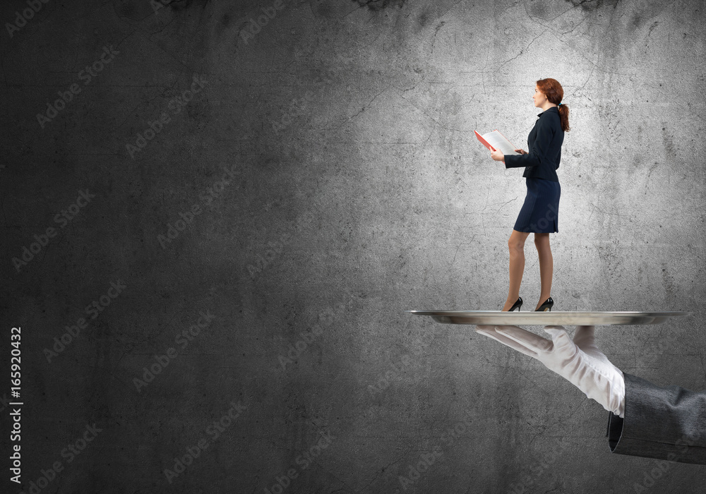 Attractive businesswoman on metal tray with red book in hands against concrete background