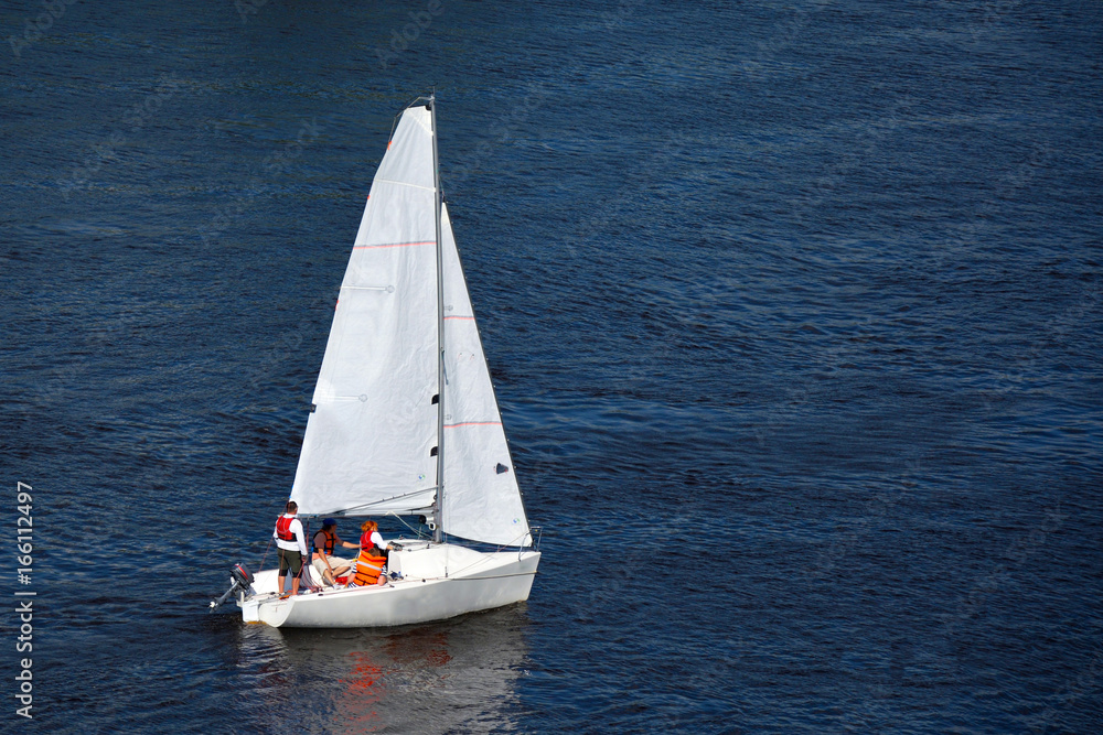 A sports yacht sails along the Siberian river in windy weather.