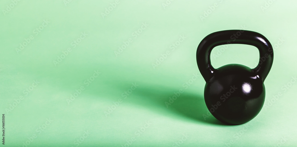 Black cast iron kettlebell on a green background