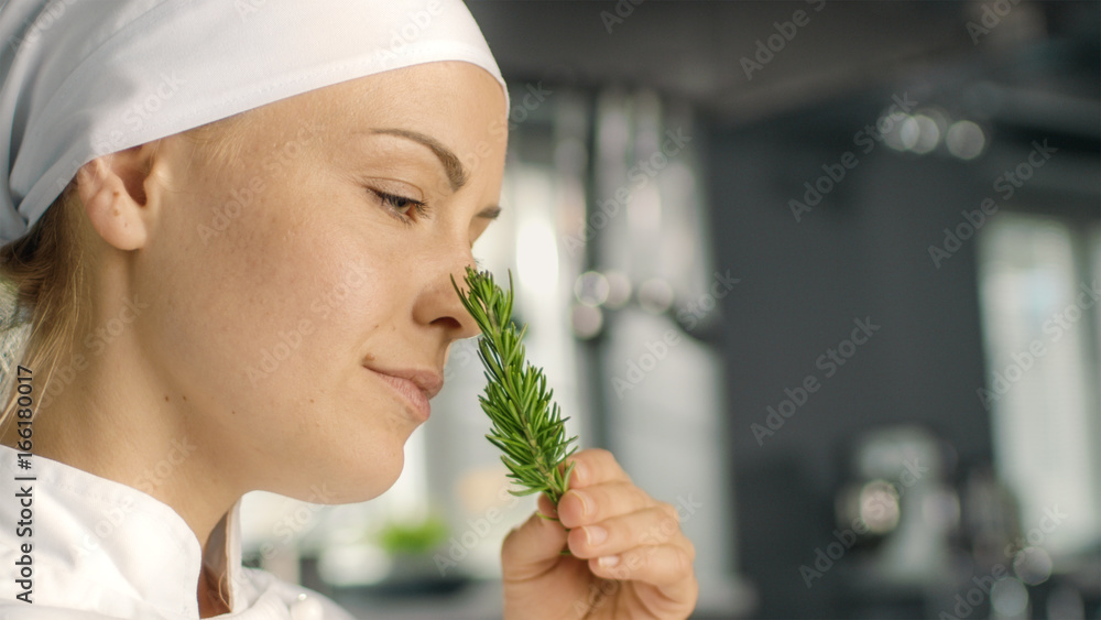 美丽的年轻女厨师闻到装饰香料植物的味道。