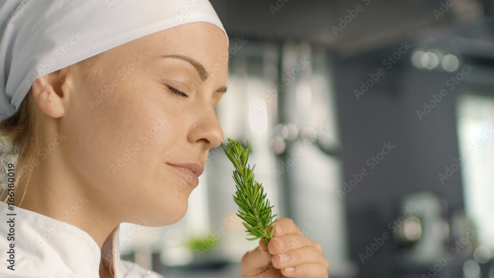 美丽的年轻女厨师闻到装饰香料植物的味道。