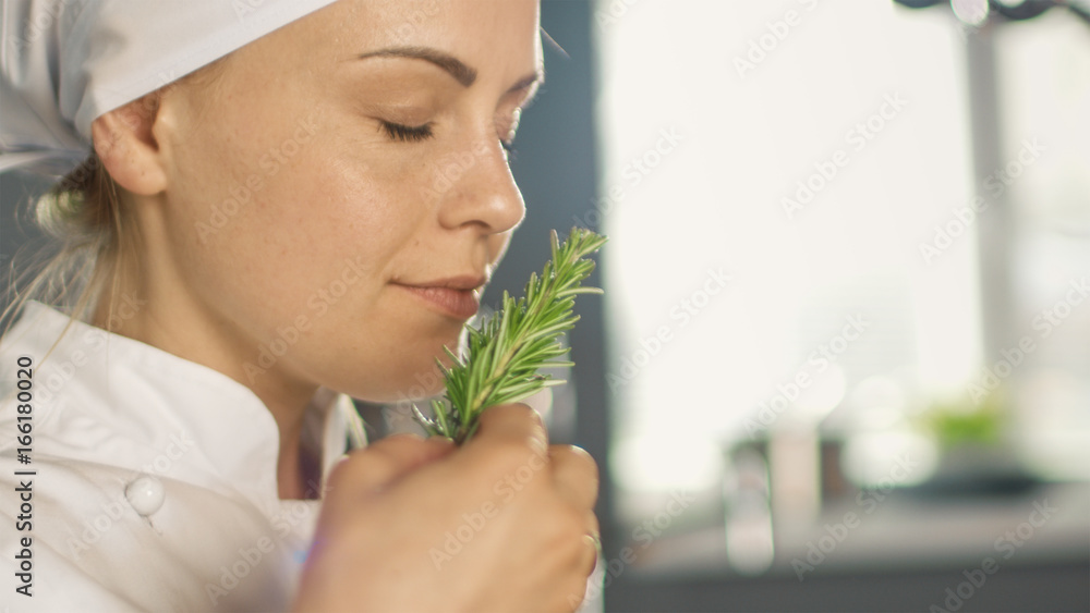 Beautiful Young Female Chef Smells Decorative Spice Plant.