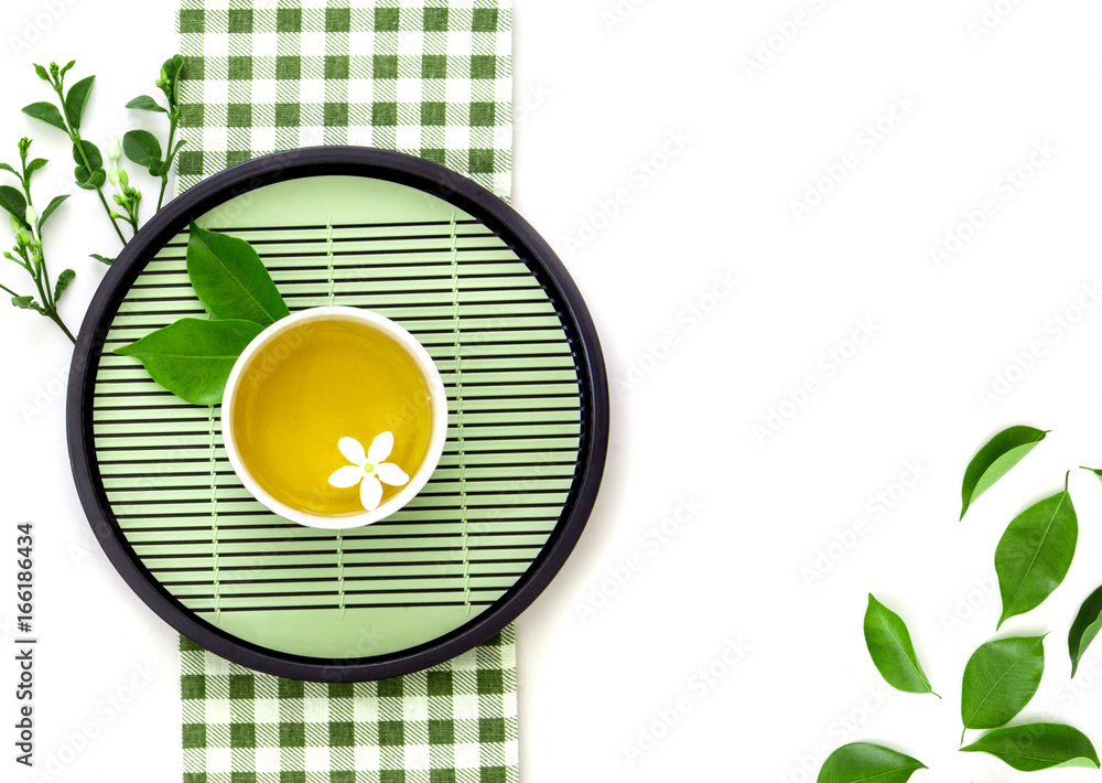 Top view shot of a hot cup of tea with green leaf decoration  with green napkin on white background 