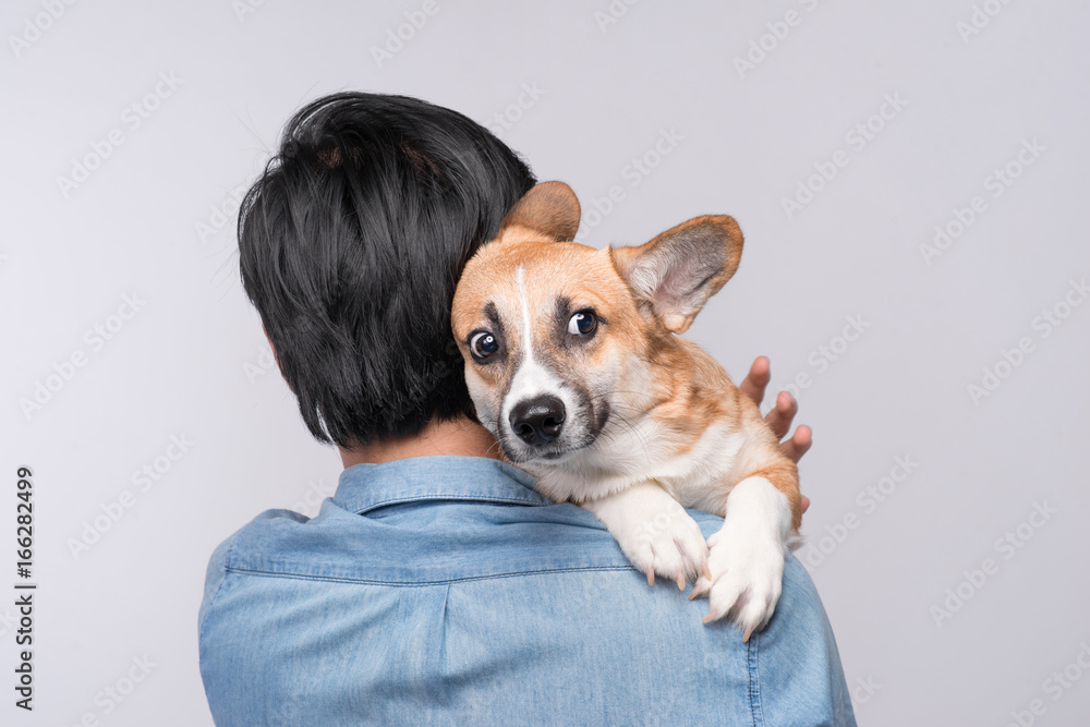 A man snuggling and hugging his dog, close friendship loving in studio background