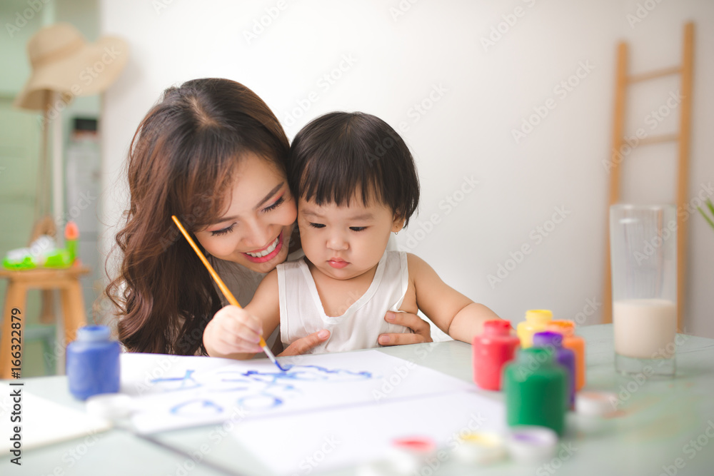 幸福的家庭，母亲和女儿一起画画。亚洲妇女帮助她的小女儿。