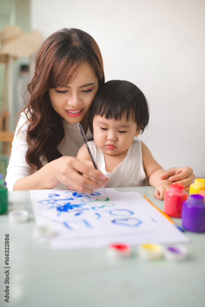 幸福的家庭，母亲和女儿一起画画。亚洲妇女帮助她的小女儿。