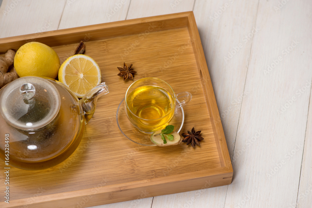 Cup of ginger tea with lemon and honey on white wooden background.