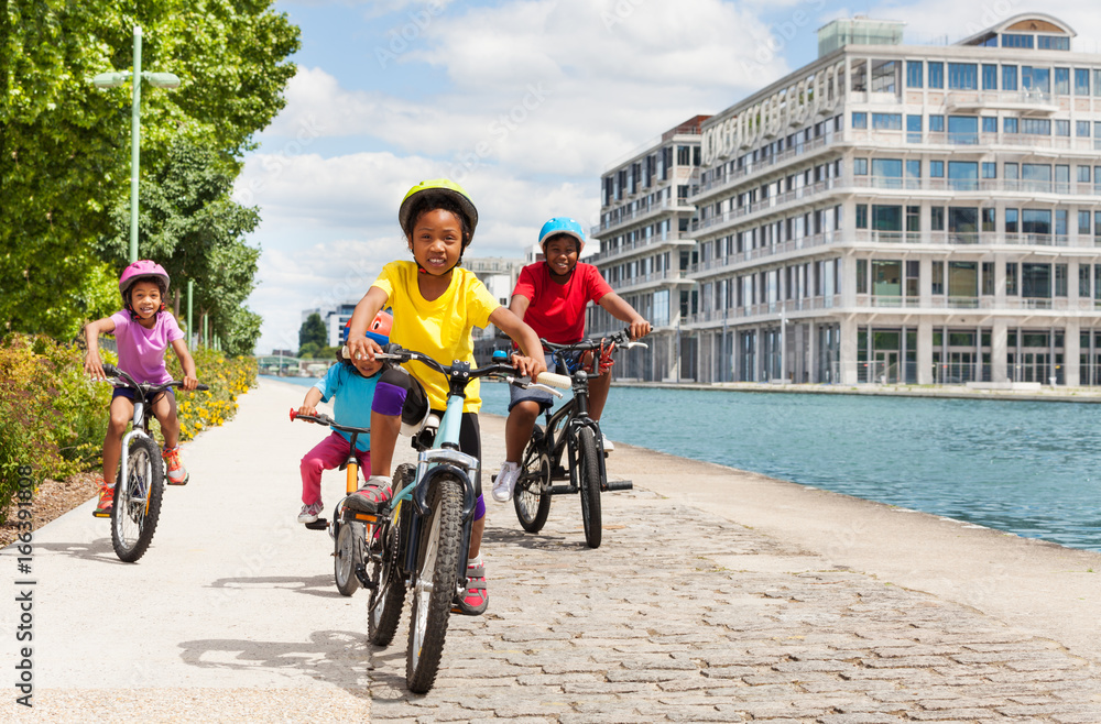 African girl cycling with friends along a river