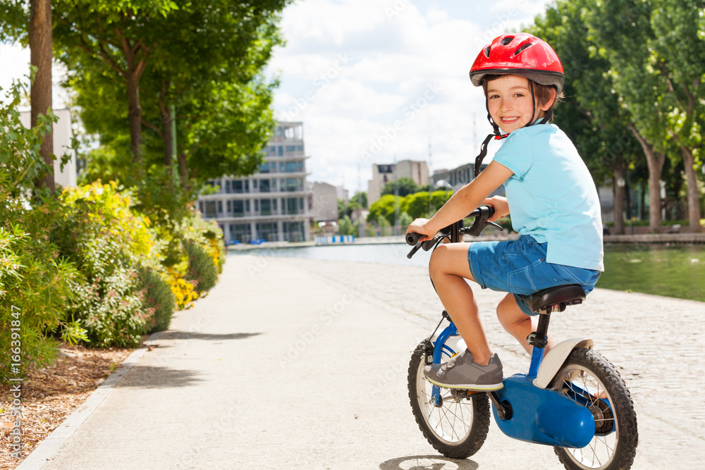 Cute little boy cycling at city park in summer