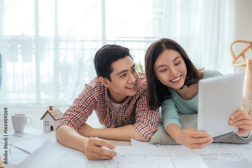 Attractive young asian adult couple looking at house plans.