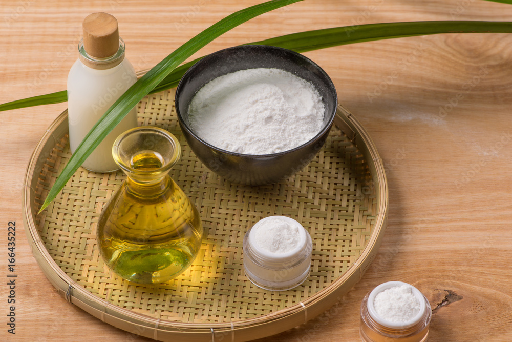 Rice flour in a wooden bowl, milk and oil with rice on the old wooden background