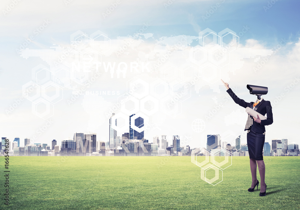 Camera headed woman standing on green grass against modern citys