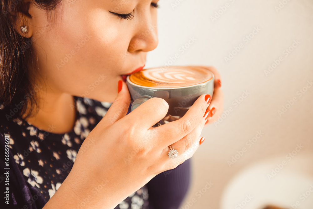 亚洲女人坐在咖啡馆喝咖啡的特写