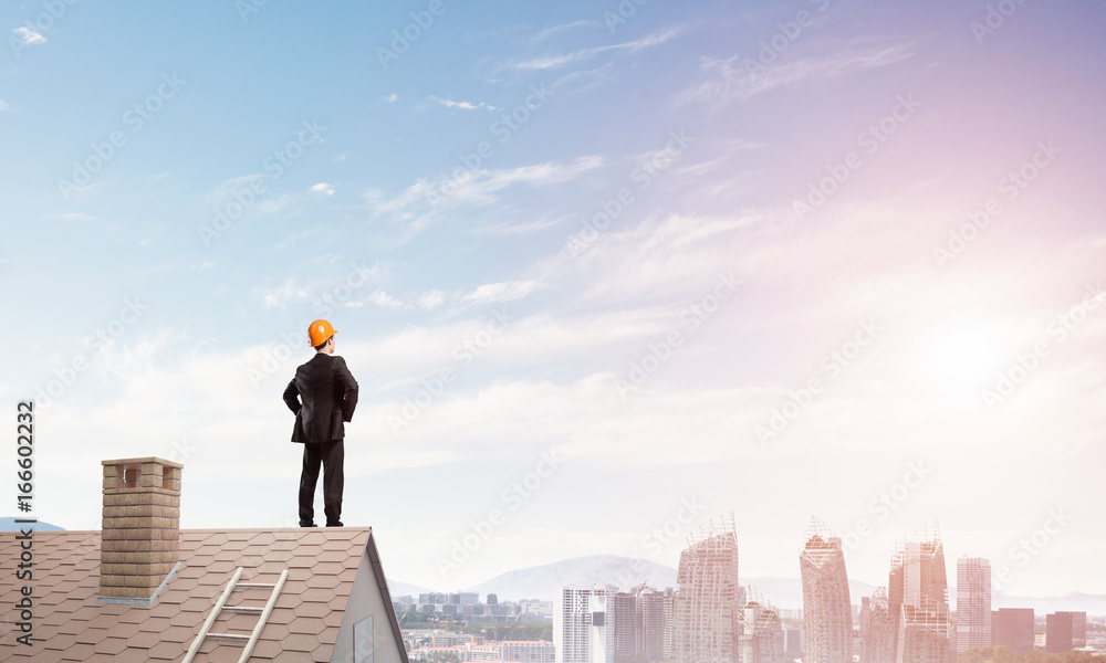 Engineer man standing on roof and looking away. Mixed media