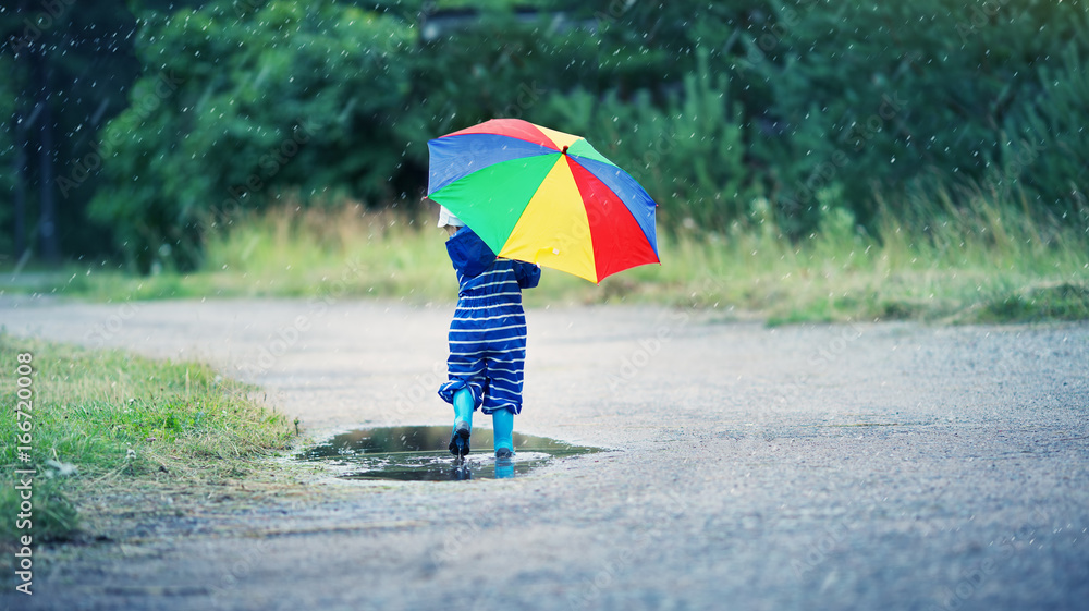 雨天孩子穿着雨鞋在水坑里行走