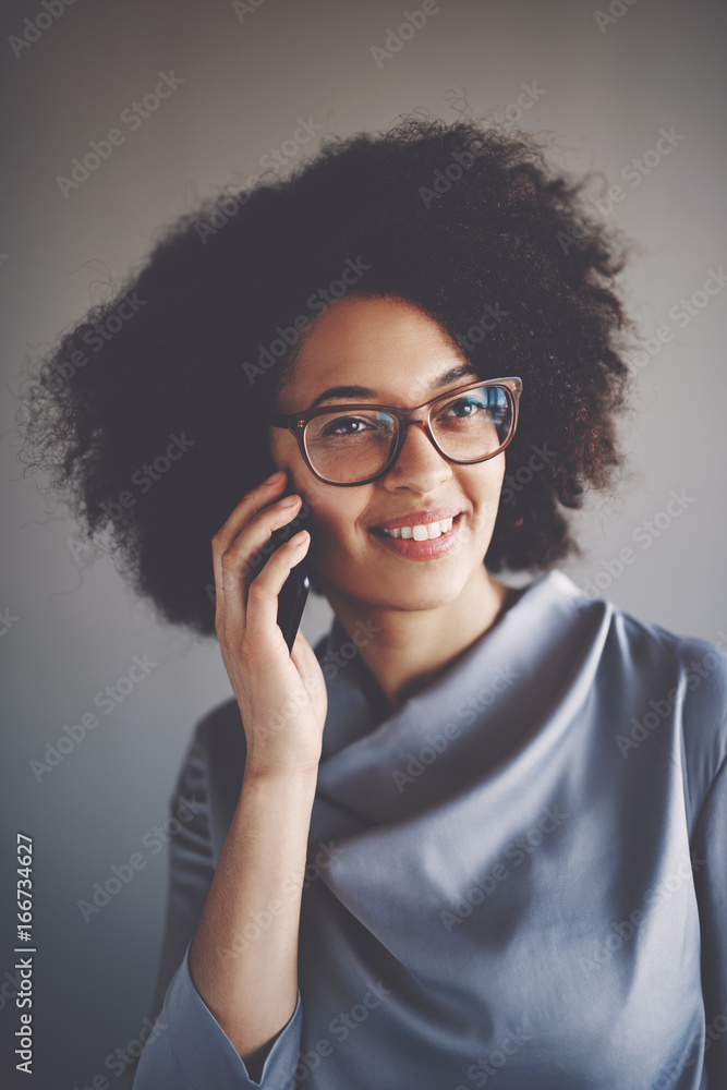 Smiling young African businesswoman talking on a cellphone