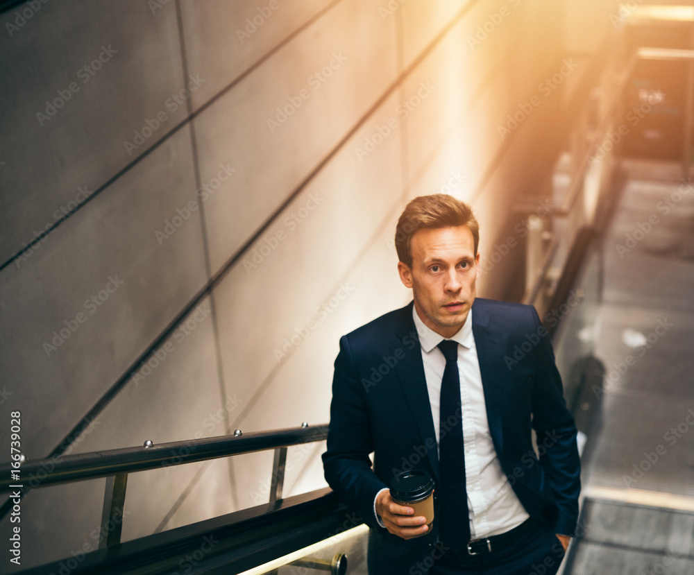 Young businessman riding an escalator during his morning commute