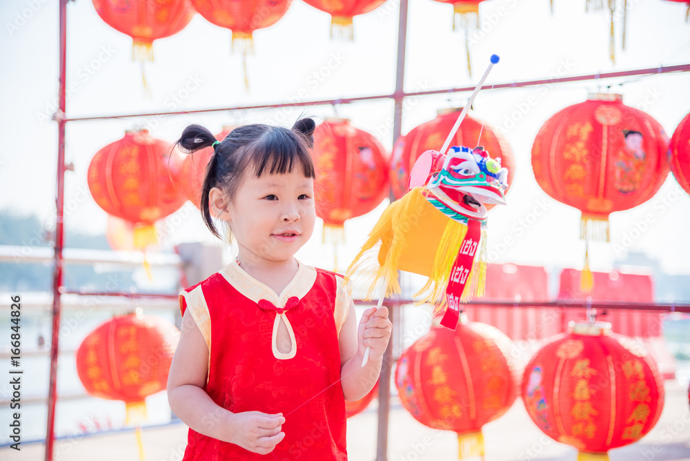 Little asian girl wearing chinese traditional costume playing toy at New year celebration festival