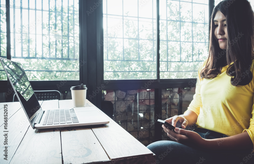 Happy Asian woman chatting on her mobile phone while relaxing in cafe during free time, Charming and