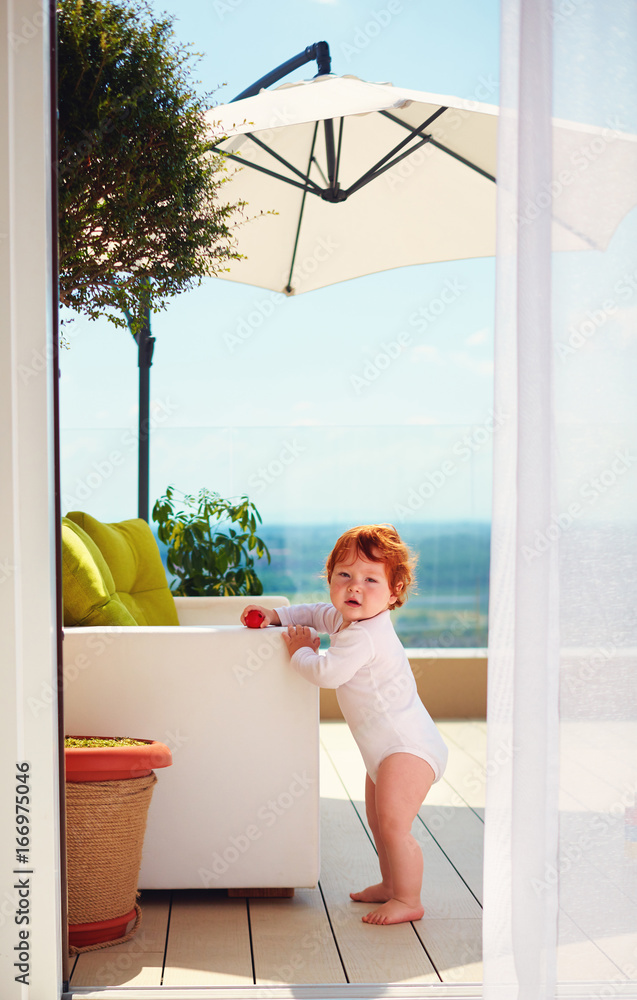 infant baby standing on rooftop patio at sunny summer day