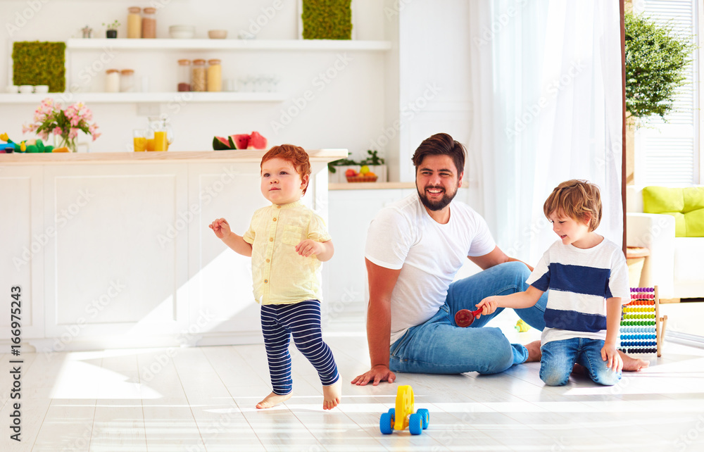 happy toddler baby playing with father and brother at home at sunny summer day